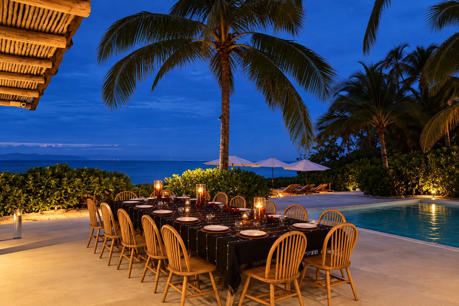 Candlelit family dinner table by the pool at a private villa in Mexico, with palm trees and the ocean at dusk